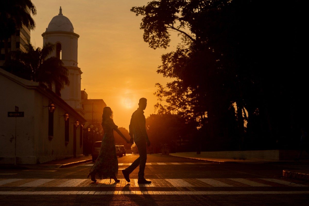 Pareja cruzando una calle al atardecer, en silueta