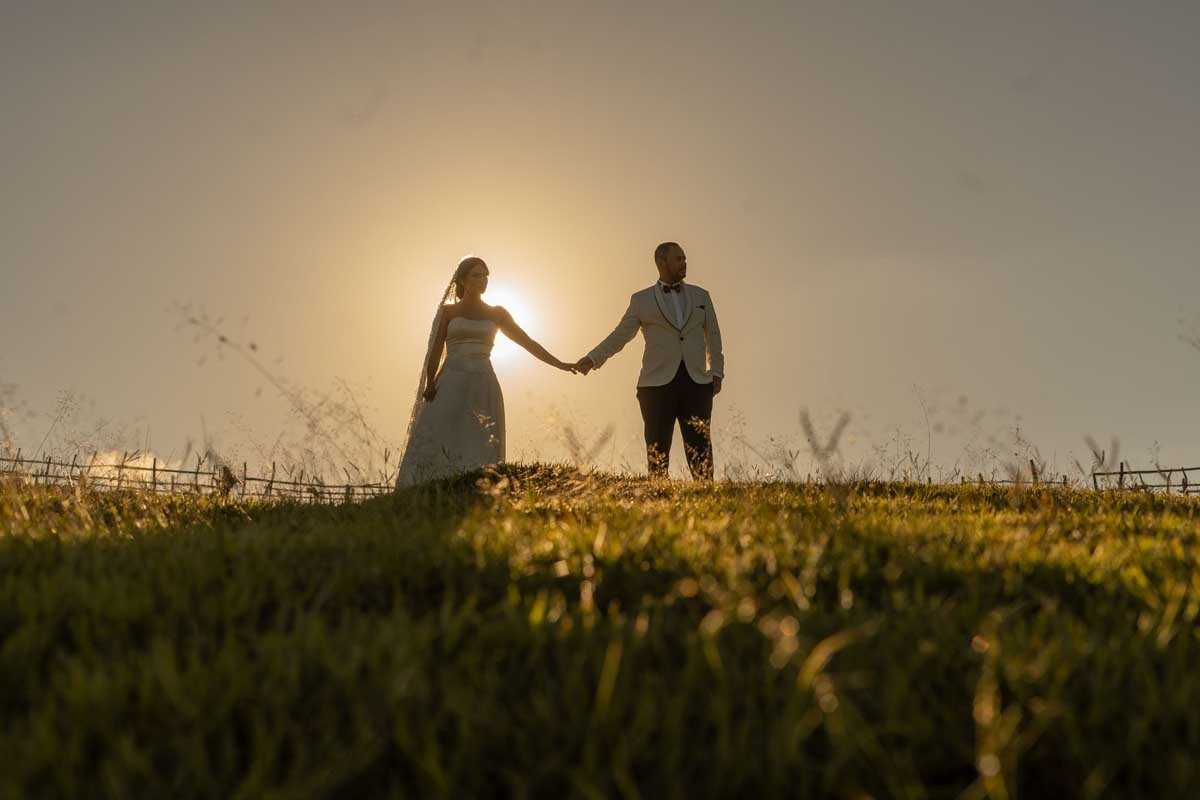 Novios tomados de la mano durante la hora dorada